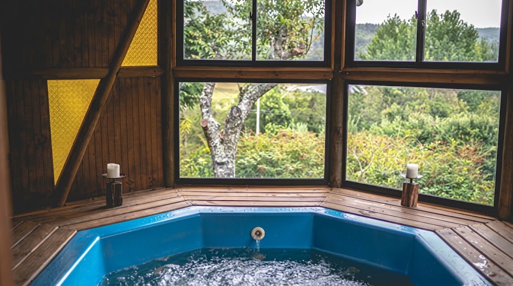 Jacuzzi de agua burbujeante empotrado en una terraza de madera, con grandes ventanales hacia la vegetación